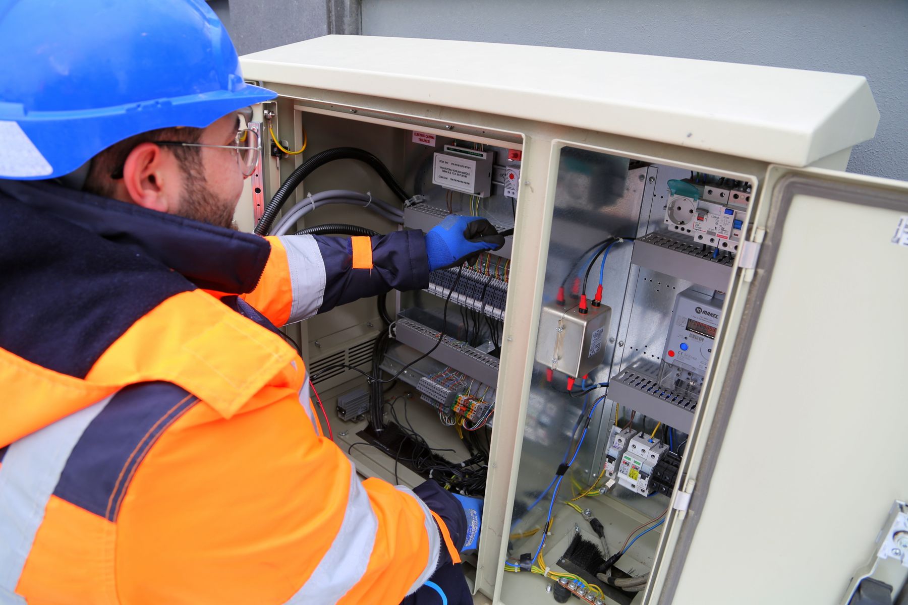 Electrician inspecting wiring connections with a flashlight and notepad