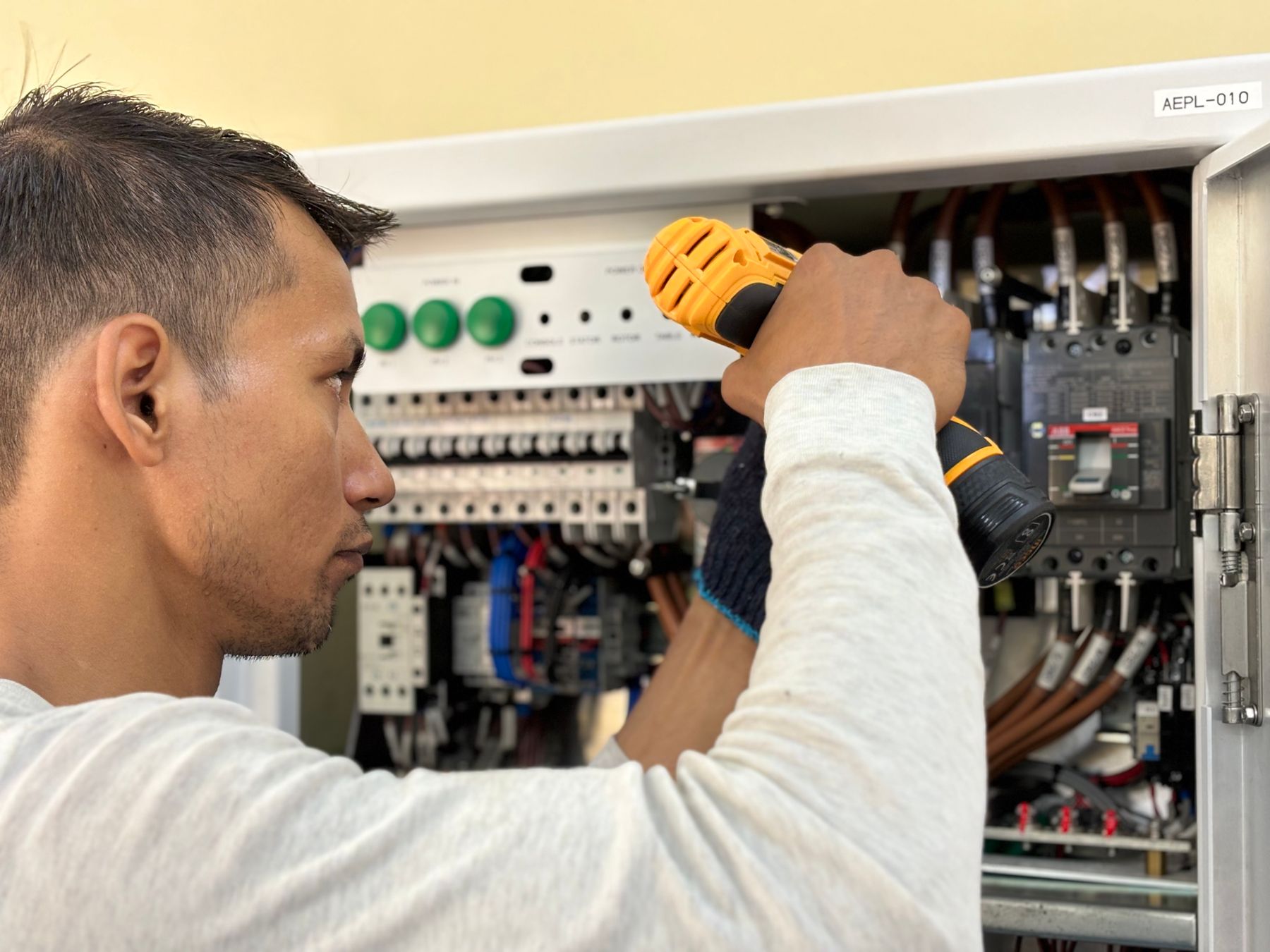Electrician working inside an open residential electrical panel with organized breakers and wiring